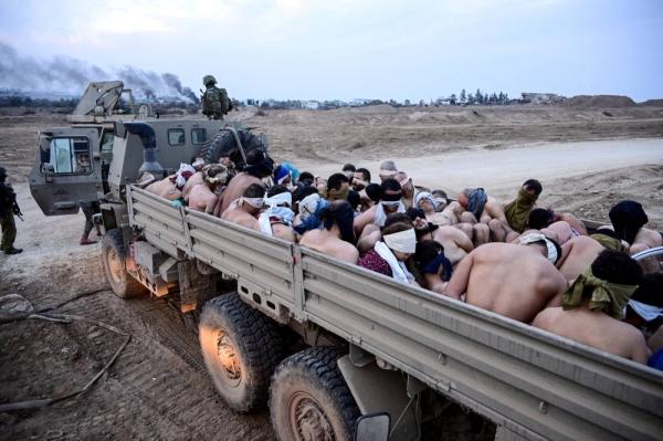 Israeli soldiers stand by a truck packed with shirtless Palestinian detainees in Gaza in December  credits: Reuters